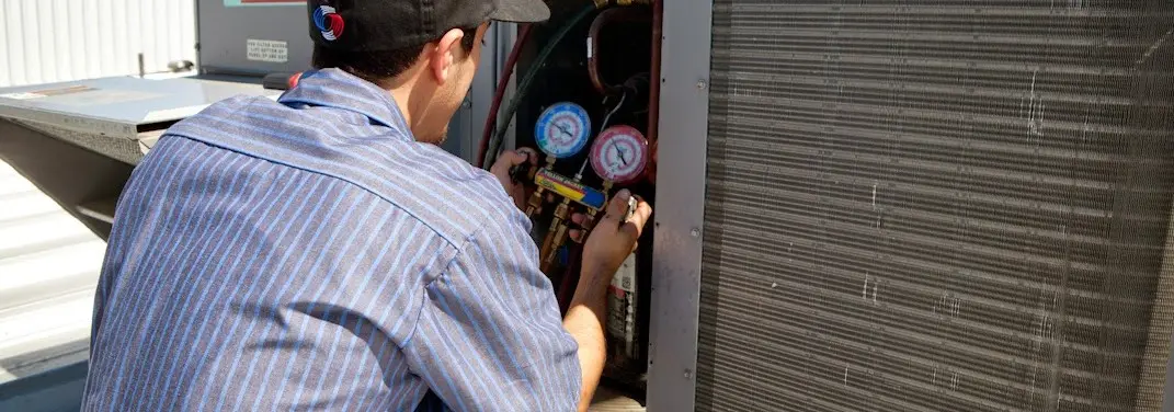 HVAC technician servicing a condenser unit in Daphne